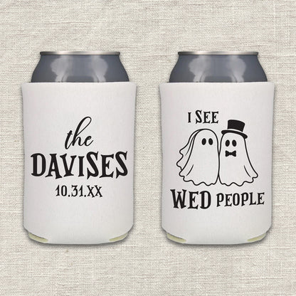 Two white can coolers are displayed side-by-side on a textured beige fabric background. The left cooler features the couple's last name and wedding date. The right can cooler features the words "I See WED People," along with bride and groom cartoon images.