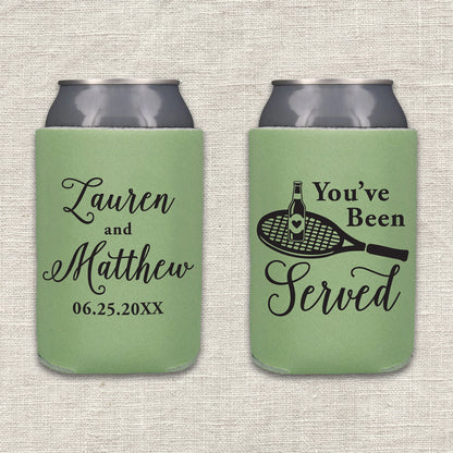 Two sage green can coolers shown side by side on a textured beige fabric background. The left can cooler is personalized with the couple's names and wedding date. The right can cooler features the text "You've Been Served" along with an image of a tennis racket with a beer bottle on it.