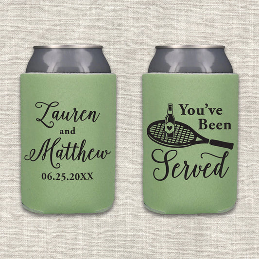 Two sage green can coolers shown side by side on a textured beige fabric background. The left can cooler is personalized with the couple's names and wedding date. The right can cooler features the text "You've Been Served" along with an image of a tennis racket with a beer bottle on it.